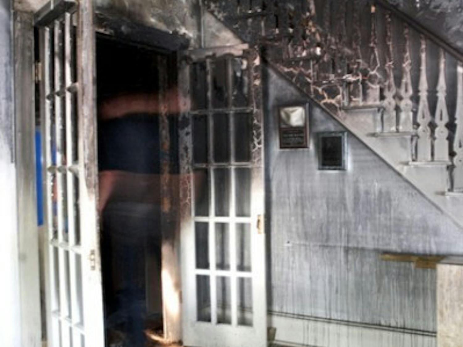 Kevin Williams, an attorney who works at the law office located in the historic Fennel-Waldo House, looks through charred remains on the floor of the office, located at 719 NE First St., which caught fire Wednesday night.
