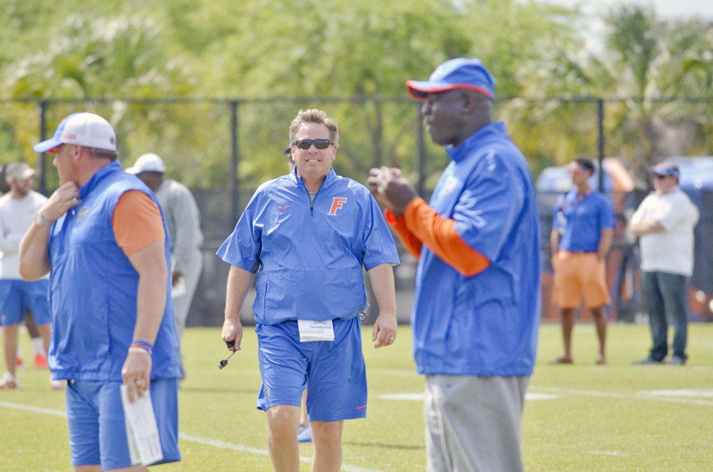 UF head football coach Jim McElwain (center) smiles during practice on Monday at Donald R. Dizney Stadium.