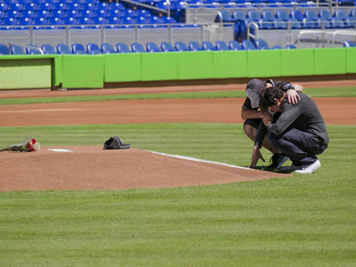 Miami Marlins player Christian Yelich, right, and teammate Justin Bour react in front of a memorial on the pitcher's mound at Marlins Park for Marlins pitcher Jose Fernanedez, Sunday, Sept. 25, 2016 in Miami. Fernandez, the ace right-hander for the Miami Marlins who escaped Cuba to become one of baseball's brightest stars, was killed in a boating accident early Sunday morning. The game between the Marlins and the Atlanta Braves was cancelled.
