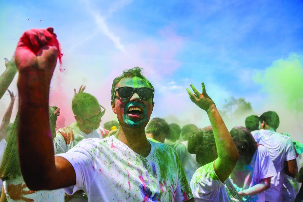 Khem B. Banjara, a 30-year-old neuro technologist at UF Health Shands Cancer Hospital, throws paint during the UF Holi Festival of Colors, organized by the UF Indian Student Association and Student Government, on Sunday afternoon. Above, more than 1,000 people attended the event, which lasted more than three hours.