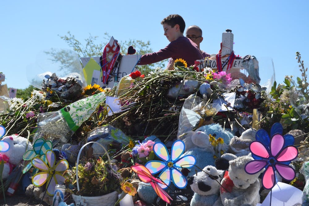 <p dir="ltr">A young boy lays down a flower at the victim’s memorials outside Marjory Stoneman Douglas High School on March 3.</p>