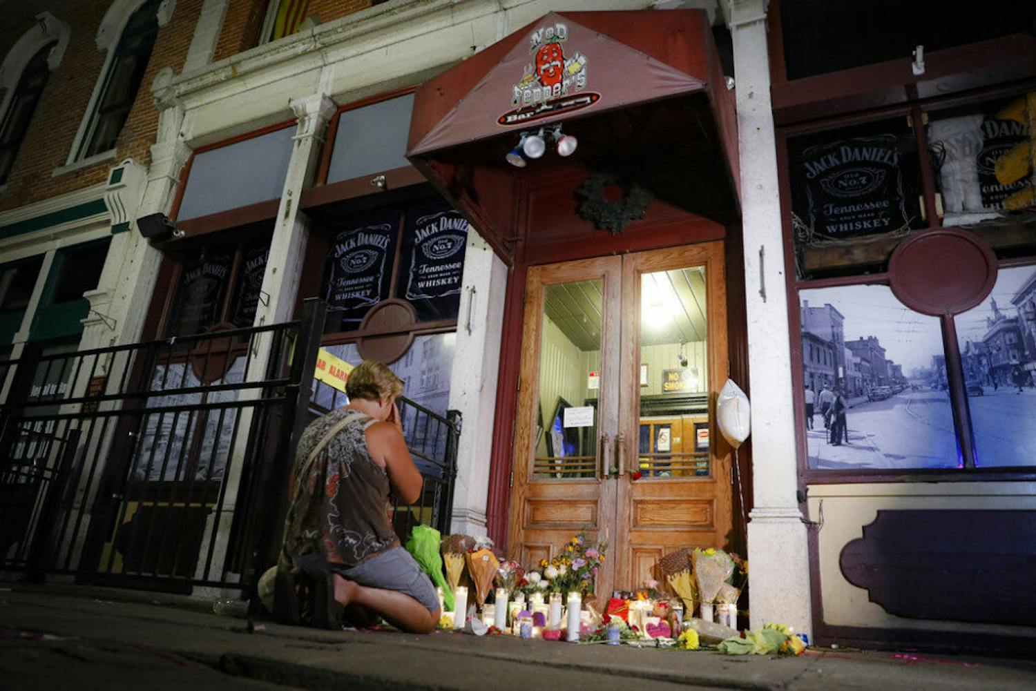 Mourners visit a makeshift memorial outside Ned Peppers bar following a vigil at the scene of a mass shooting, Sunday, Aug. 4, 2019, in Dayton, Ohio. A masked gunman in body armor opened fire early Sunday in the popular entertainment district in Dayton, killing several people, including his sister, and wounding dozens before he was quickly slain by police, officials said.&nbsp;