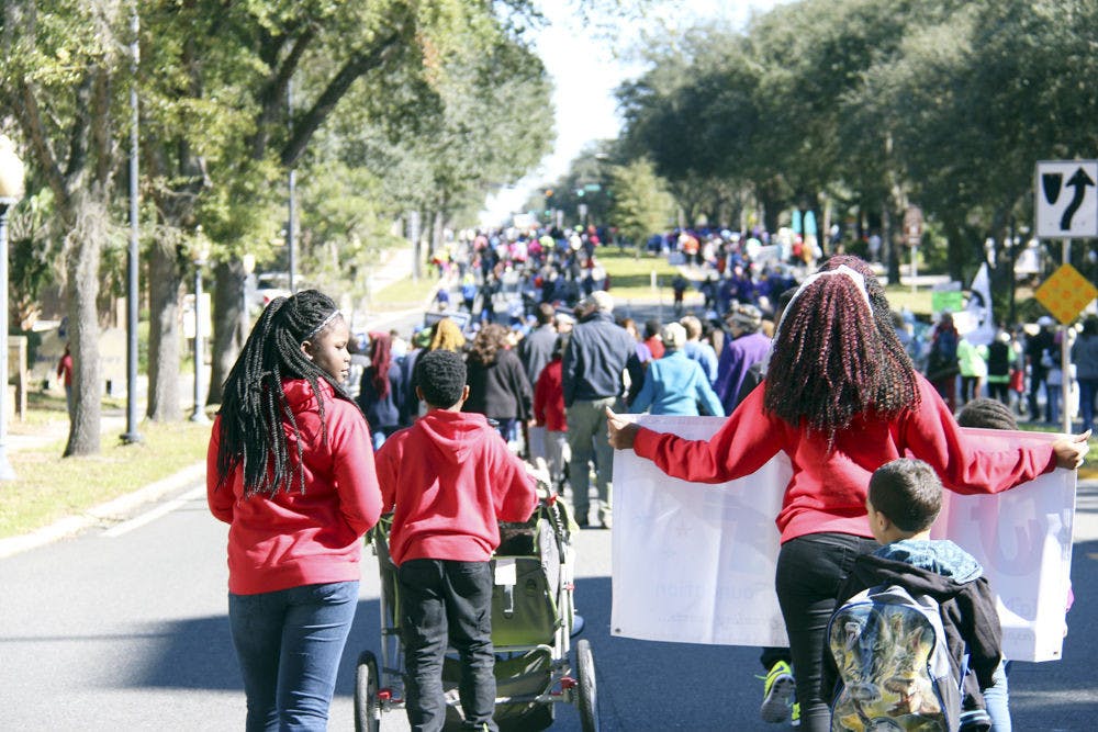 Hundreds of people showed their support for Martin Luther King Jr. and the equality for which he stood by walking east down University Avenue on Jan. 18, 2016. Some held signs for other causes they supported, such as stricter gun laws or mayoral candidates in Gainesville, while others walked with friends from church and sang impromptu, uplifting songs along the way.