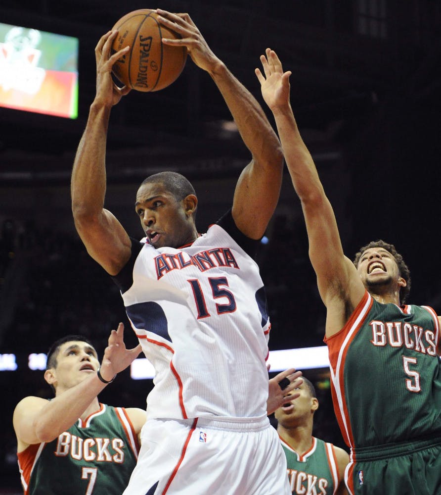 Atlanta Hawks' Al Horford (15) pulls down a rebound over Milwaukee Bucks' Ersan Ilyasova (7) and Michael Carter-Williams (5) in the first half of an NBA basketball game Monday, March 30, 2015, in Atlanta.