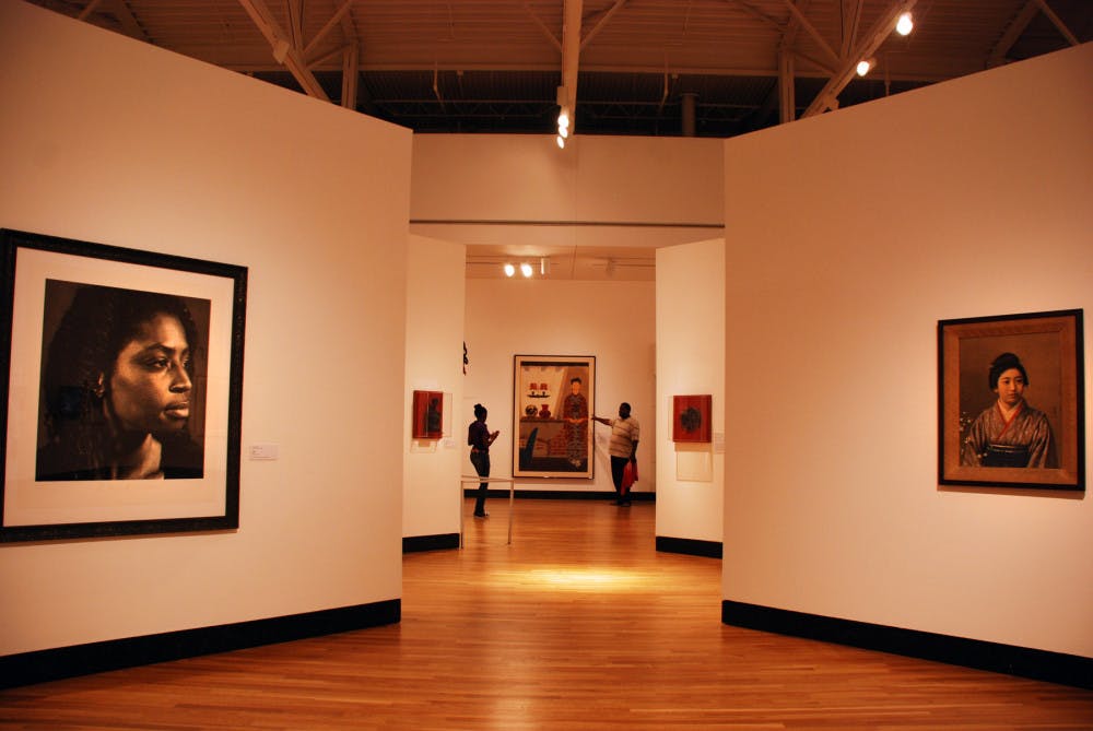 <p>Participants of the Much Ado About Portraits exhibition stop to examine the various faces splashed across the canvases at the Harn Museum. North Central Florida high school students also have the opportunity to be a part of the virtual exhbition by submitting a portrait to be displayed electronically.</p>