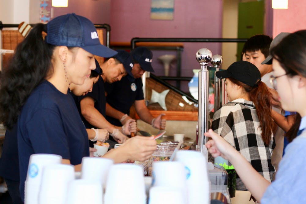 Mr. Cool Ice Cream employees serve rolled ice cream to customers at its Grand Opening event on Thursday. The line was out the door on Saturday evening. 