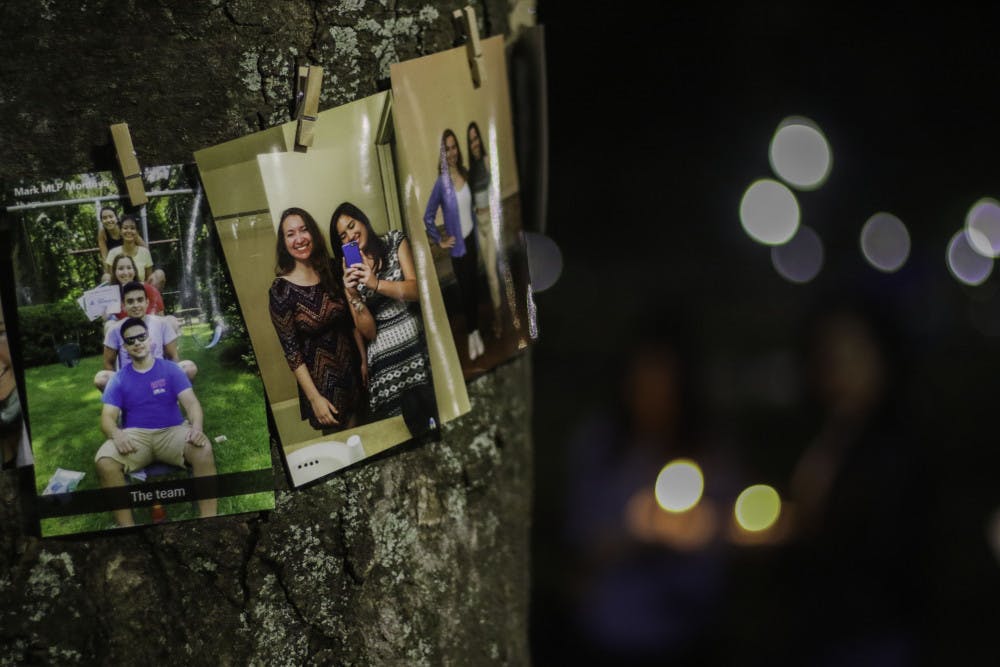 Pictures of Sophia Visent, a 22-year-old environmental management fourth year, are pinned on a tree Wednesday night as friends and family mourn her death with a candlelight vigil. 