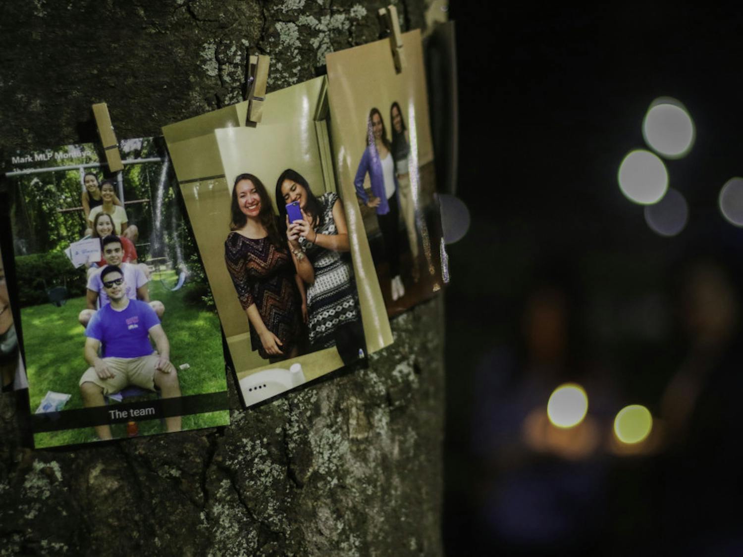 Pictures of Sophia Visent, a 22-year-old environmental management fourth year, are pinned on a tree Wednesday night as friends and family mourn her death with a candlelight vigil.