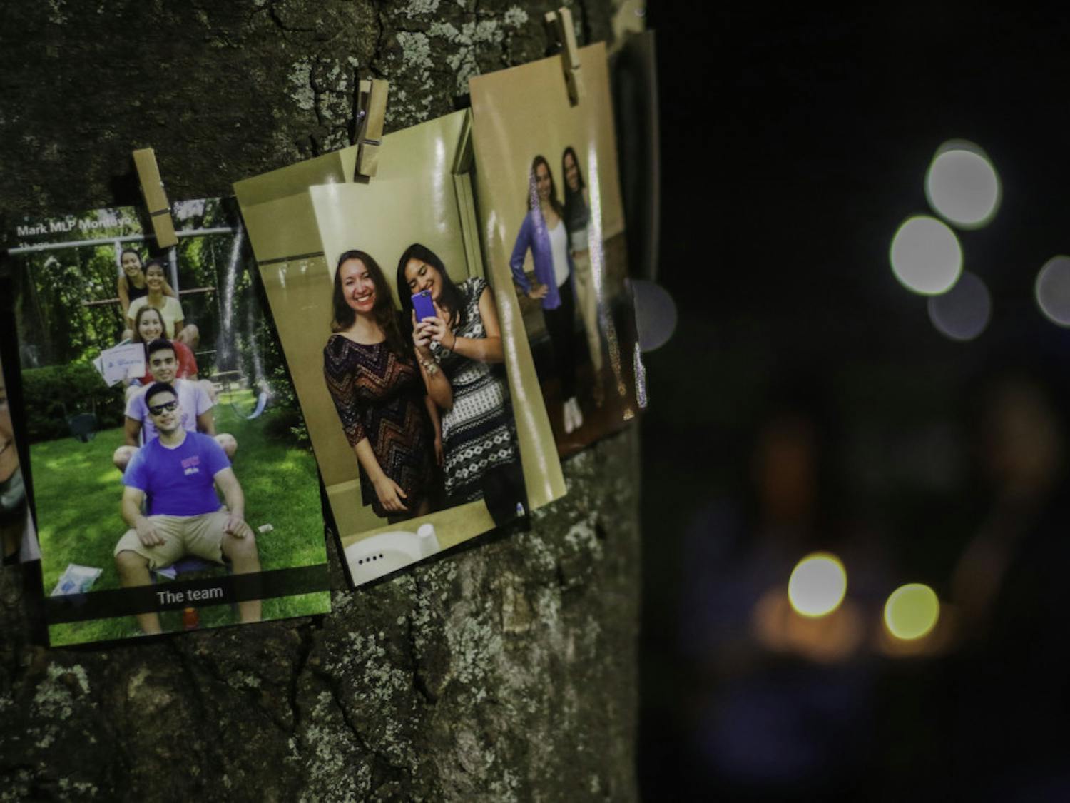 Pictures of Sophia Visent, a 22-year-old environmental management fourth year, are pinned on a tree Wednesday night as friends and family mourn her death with a candlelight vigil. 