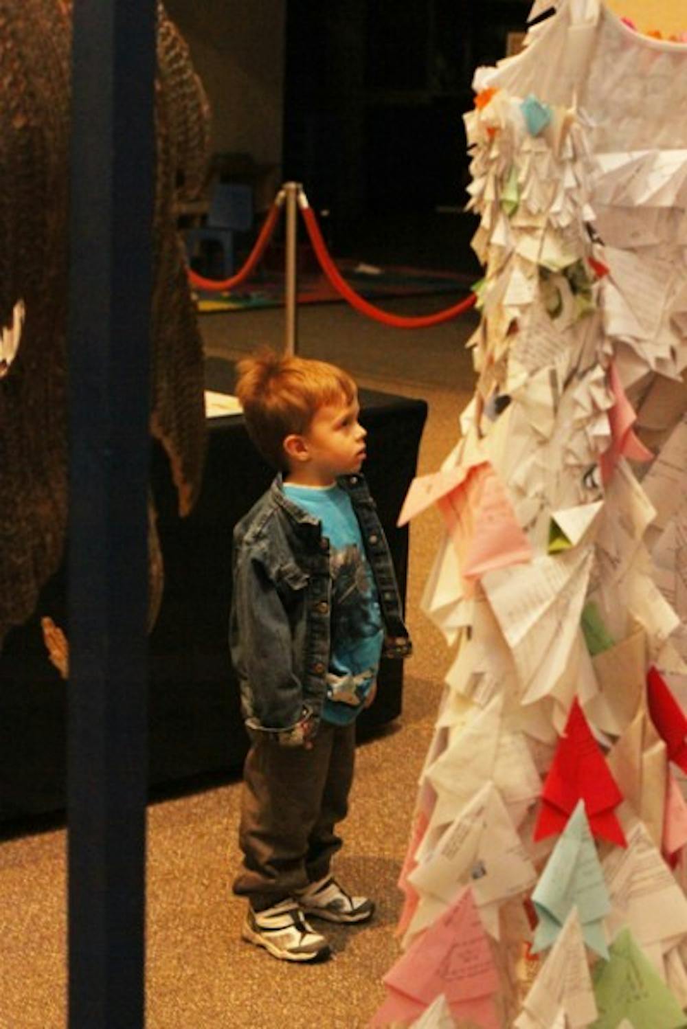 <p>Alex Britch, 3, looks at dresses made of recycled papers and bags at the student recycled-art competition, Trashformations, at the Florida Museum of Natural History on Friday.</p>