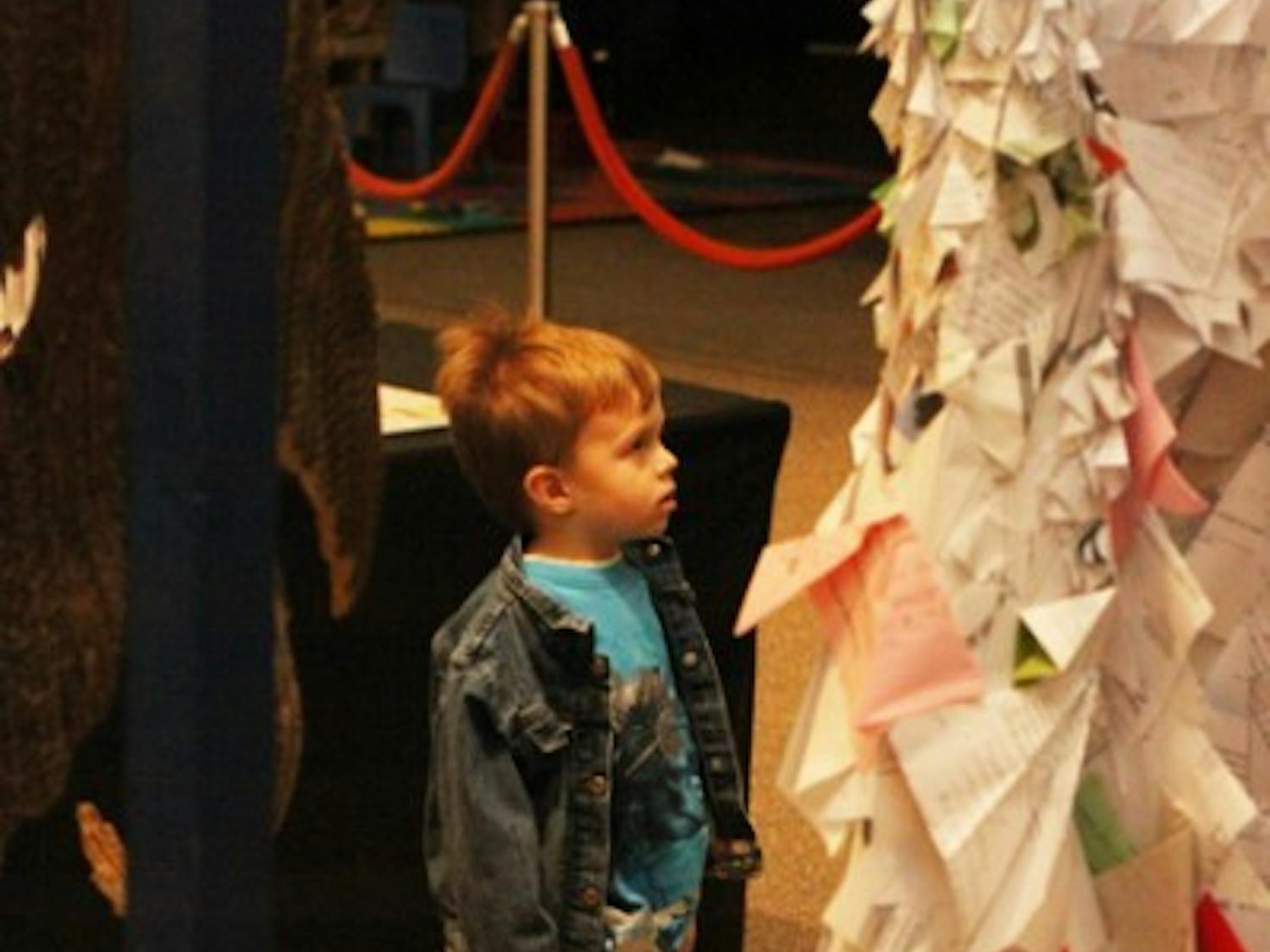 Alex Britch, 3, looks at dresses made of recycled papers and bags at the student recycled-art competition, Trashformations, at the Florida Museum of Natural History on Friday.