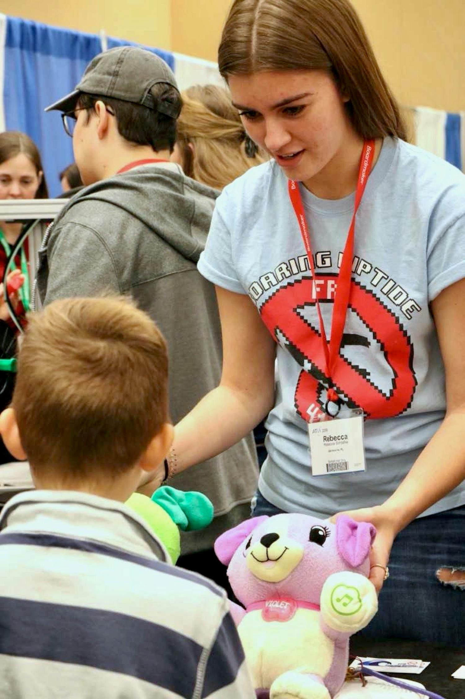 A student from P.K. Yonge Developmental Research School’s First Robotics Club, 12th-grader Rebecca Schlafke, demonstrates how to use the club’s adapted creations to a child at the Assistive Technology Industry Association Maker's Day on Saturday. 