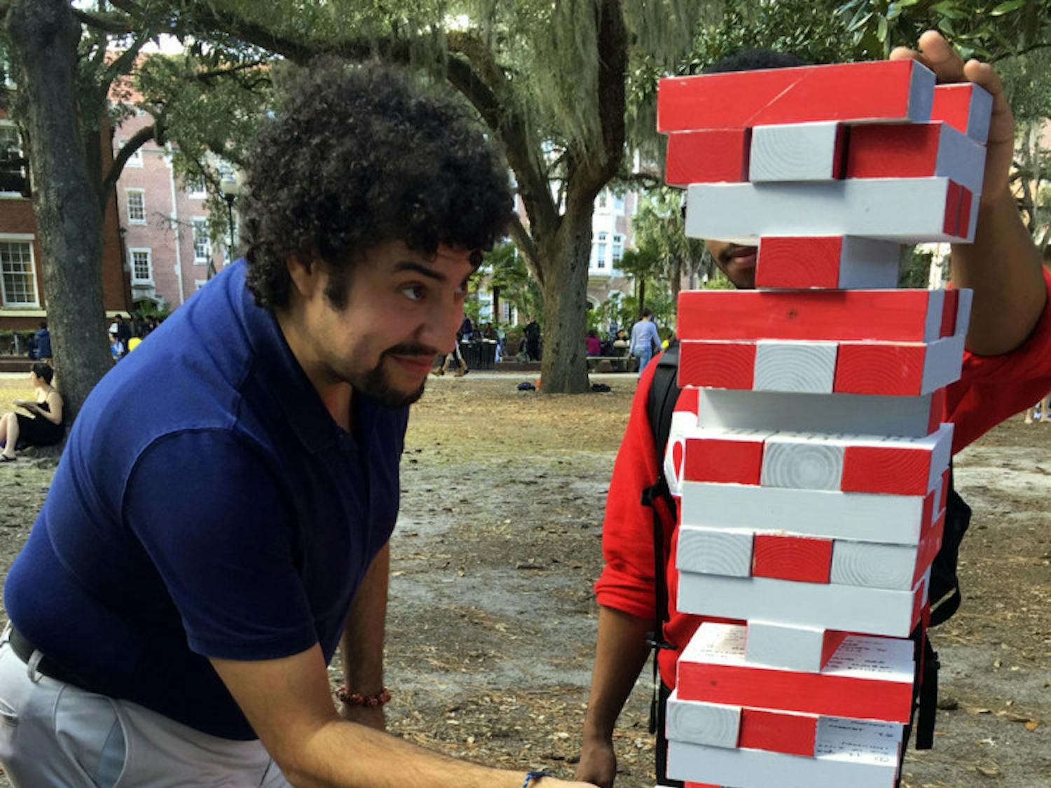 Rafael Cruzado, 27, an employee at UF’s multicultural affairs, takes a piece from Omega Delta Phi held its first “Jiant Jenga” game. Each of the 60 silver and red pieces had a fact about human trafficking written on it.