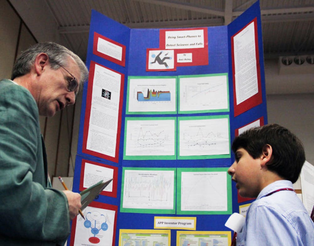 <p>Twelve-year-old Amir Helmy, a seventh-grader at Lincoln Middle School, explains his project, which uses smartphones to detect seizures and falls, to judge Alex Angerhofer, at this year’s Alachua Region Science and Engineering Fair at Santa Fe College.</p>