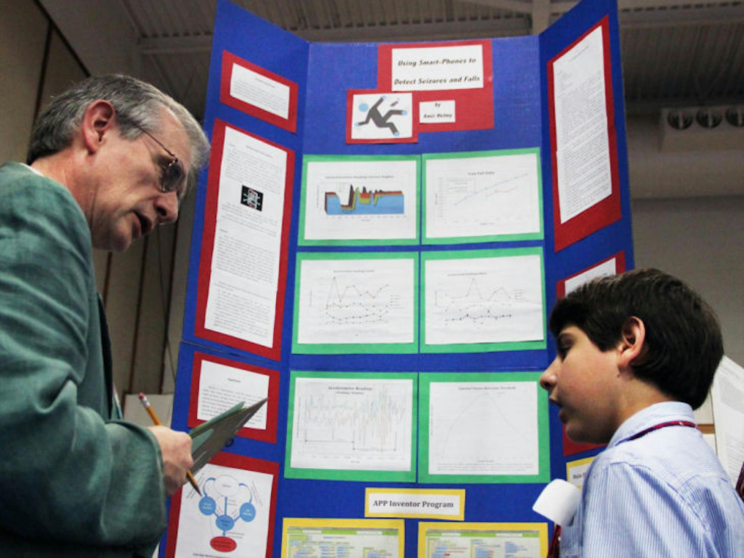 Twelve-year-old Amir Helmy, a seventh-grader at Lincoln Middle School, explains his project, which uses smartphones to detect seizures and falls, to judge Alex Angerhofer, at this year’s Alachua Region Science and Engineering Fair at Santa Fe College.