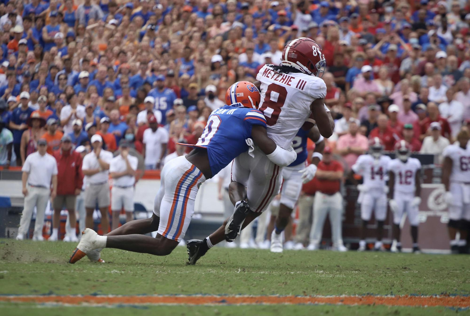 Safety Trey Dean III, pictured in blue, tackles Alabama wide receiver John Metchie III after he makes a catch. 