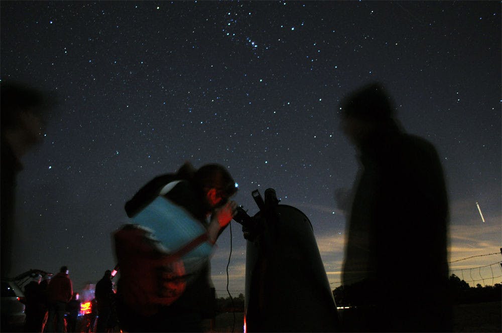 UF materials science associate professor Richard Hennig, 42, watches over an attendee of Stargazing at Paynes Prairie on Saturday. Hennig set his telescope to focus on the Orion Nebula, which a collection of dust and gas lit up by surrounding stars.