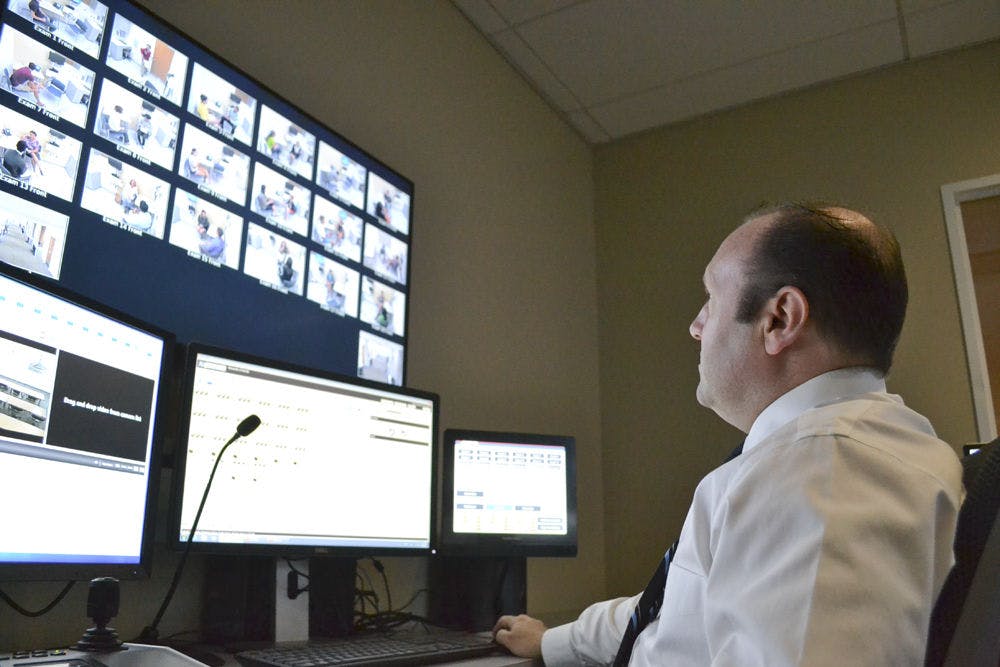 Dan Pollock, the head internet technician at the Anaclerio Learning and Assessment Center, gazes upon 18 screens streaming live footage of first year medical students interacting with volunteers acting as patients Aug. 28, 2015. Pollock’s voice, jokingly called the voice of “God,” can be heard in the halls of the center instructing students during their lesson.