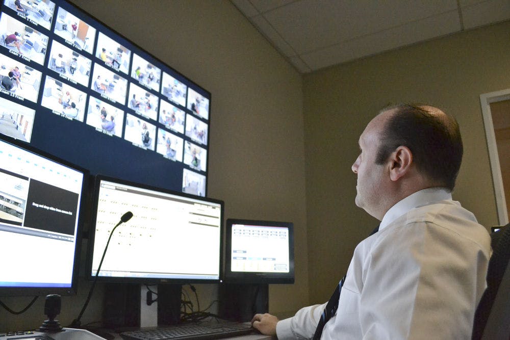 <p>Dan Pollock, the head internet technician at the Anaclerio Learning and Assessment Center, gazes upon 18 screens streaming live footage of first year medical students interacting with volunteers acting as patients Aug. 28, 2015. Pollock’s voice, jokingly called the voice of “God,” can be heard in the halls of the center instructing students during their lesson.</p>