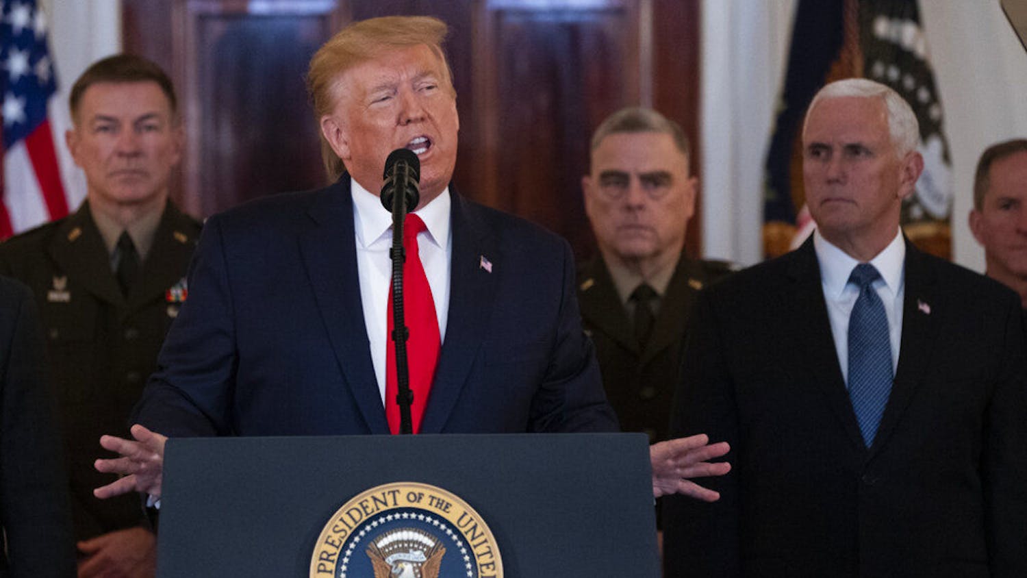 President Donald Trump addresses the nation from the White House on the ballistic missile strike that Iran launched against Iraqi air bases housing U.S. troops, Wednesday, Jan. 8, 2020, in Washington, as Chairman of the Joint Chiefs of Staff Gen. Mark Milley, Vice President Mike Pence, and others look on. (AP Photo/ Evan Vucci)