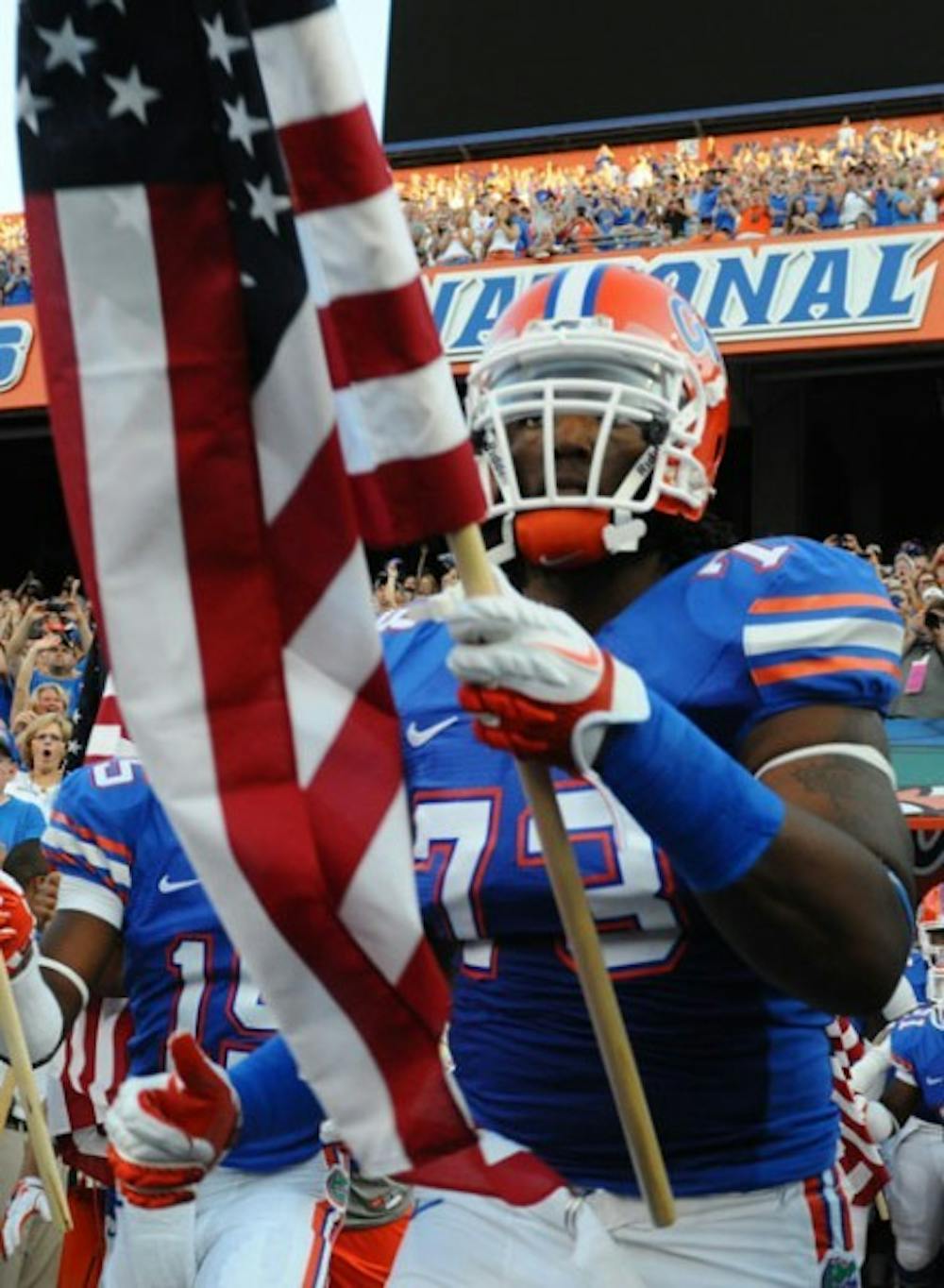 <p>Gators offensive lineman Xavier Nixon, whose parents both have military backgrounds, was one of eight players to carry a flag on Saturday.</p>