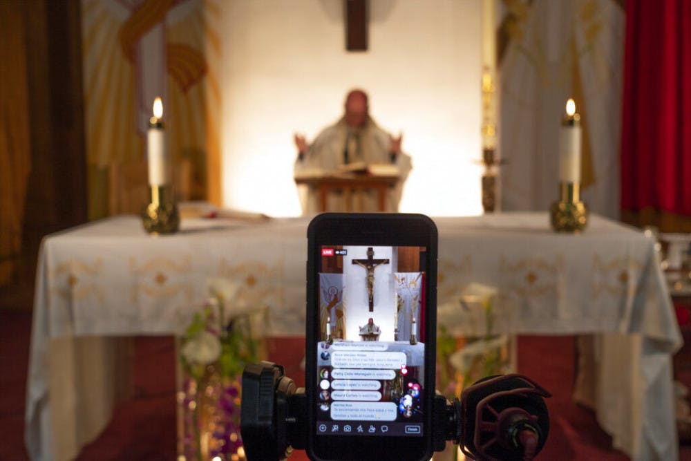 <p>Pastor Nicolas Sanchez is seen on his iPhone used to live-stream in celebration of Easter Vigil Mass at St. Patrick Church in North Hollywood, Calif., on Saturday, April 11, 2020. The COVID-19 measures also have changed the way people worship, with churches and synagogues closed and many Passover and Easter services streamed online. (AP Photo/Damian Dovarganes)</p>