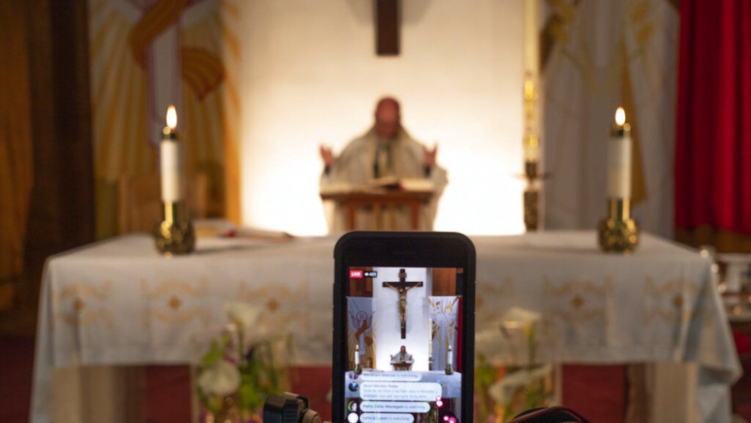 Pastor Nicolas Sanchez is seen on his iPhone used to live-stream in celebration of Easter Vigil Mass at St. Patrick Church in North Hollywood, Calif., on Saturday, April 11, 2020. The COVID-19 measures also have changed the way people worship, with churches and synagogues closed and many Passover and Easter services streamed online. (AP Photo/Damian Dovarganes)