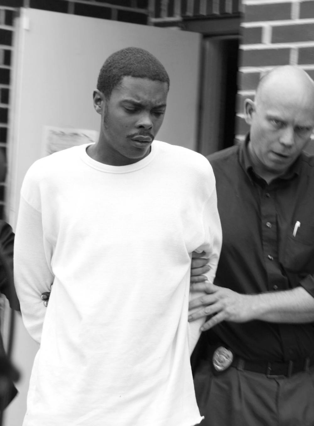 <p>Marcus S. Brantley, 21, who was arrested and charged with home invasion robbery, walks to a police car Thursday morning.</p>