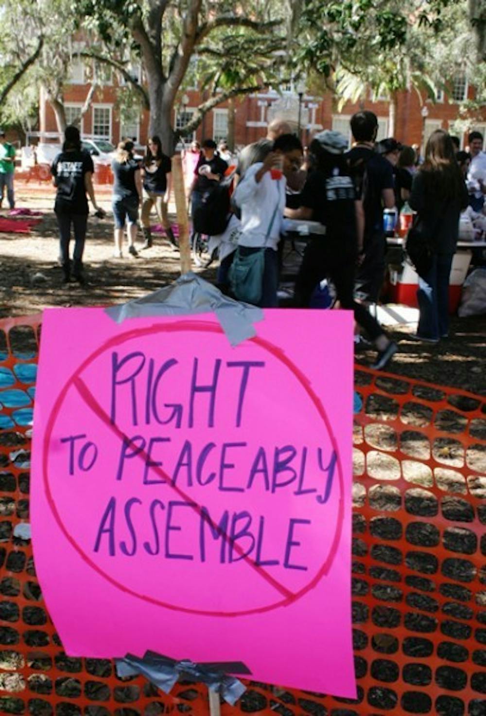 <p>A sign reading "Right To Peaceably Assemble" with a cross through it is posted at the First Amendment Free Food Festival on the Plaza of the Americas Wednesday afternoon.</p>