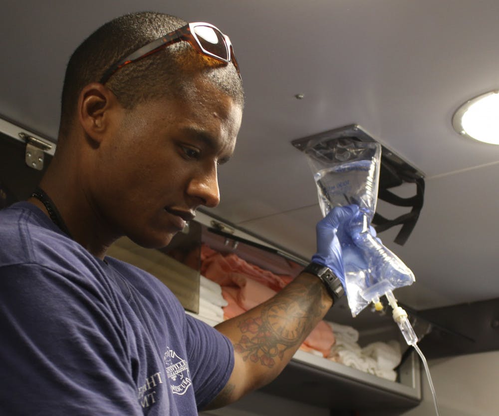 Gunnar Piner, a 28-year-old firefighter EMT and driver, helps start the flow of fluids into a patient’s arm who is being transported to the hospital in an ambulance. The woman’s heartbeat was fluctuating and during the transit she asked another paramedic, Andrew Picklo, “I ain’t gonna die, am I?” Picklo then reassured her while working to steady her condition, “No ma'am, you’re not going to die.”