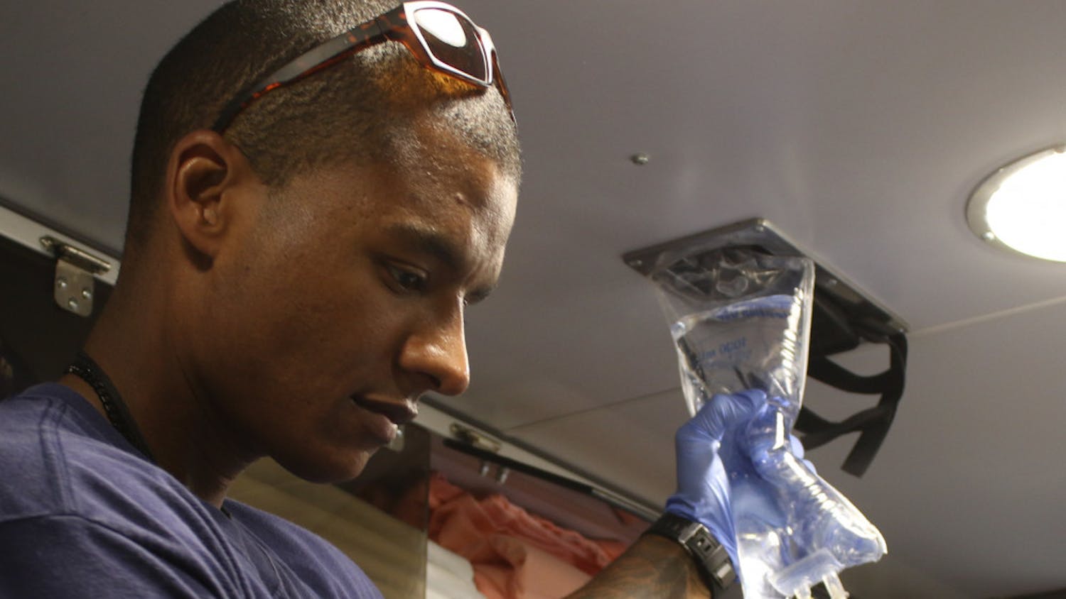 Gunnar Piner, a 28-year-old firefighter EMT and driver, helps start the flow of fluids into a patient’s arm who is being transported to the hospital in an ambulance. The woman’s heartbeat was fluctuating and during the transit she asked another paramedic, Andrew Picklo, “I ain’t gonna die, am I?” Picklo then reassured her while working to steady her condition, “No ma'am, you’re not going to die.”
