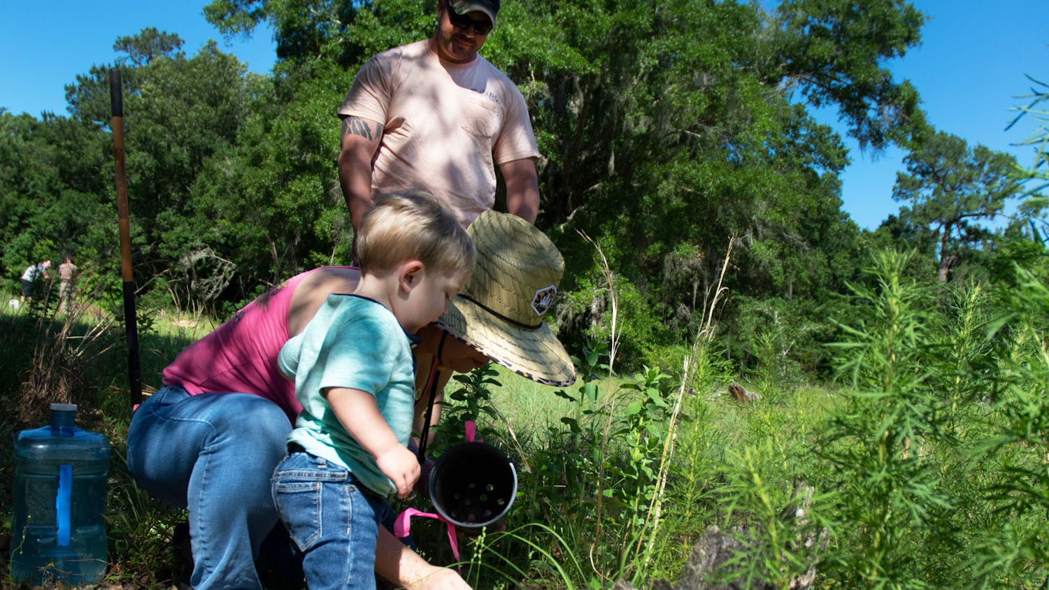 Jillian Rexroat and son, Jaxson Rexroat, (left) arrange dirt as Matt Rexroat (right) smiles at the two of them at his grandmother-in-law’s grave in the Prairie Creek Conservation Cemetery on Saturday, May 15, 2021. The family was there for Community Planting Day in the meadow area of the cemetery. 