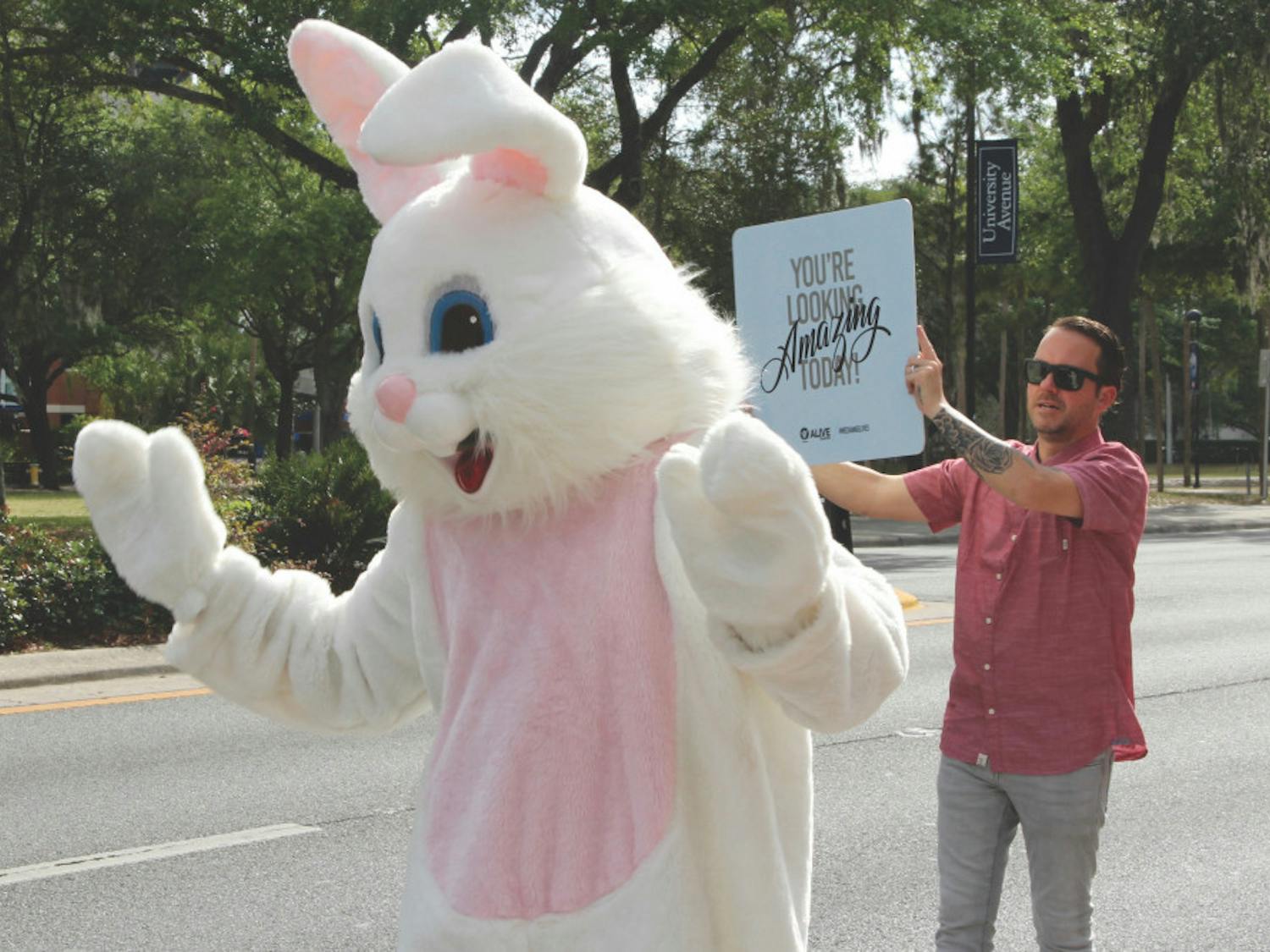 The Easter Bunny and Charles Young, pastor of Alive Church, located at 1826 W. University Ave., wave to passing drivers before heading inside for an evening service.
