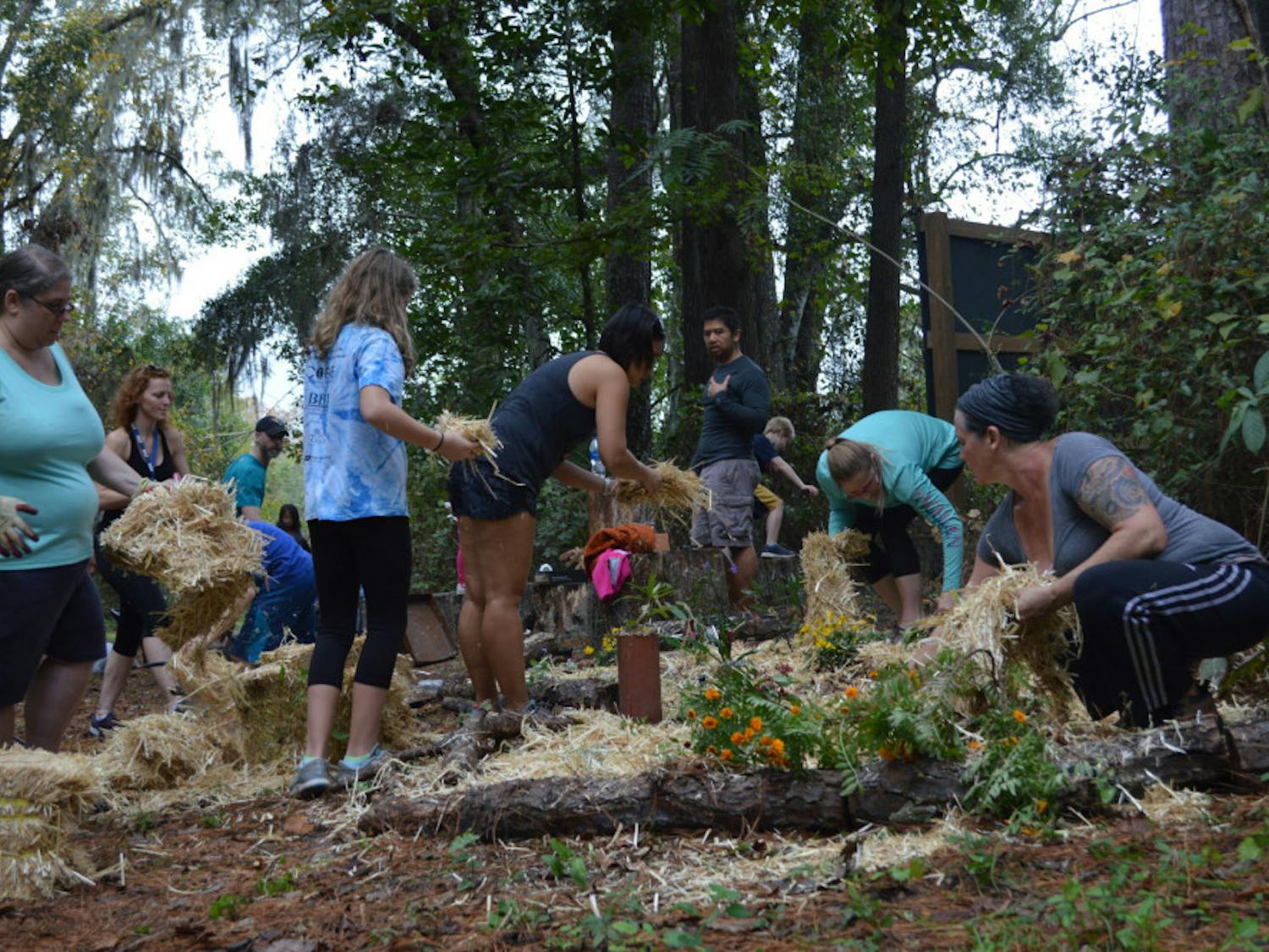 Volunteers spread hay after planting marigolds, milkweed and other perennials beside an outdoor classroom at Stephen Foster Elementary School. They took the day to beautify the campus in the wake of media specialist Leslie Williams’ death. Gillian Sweeney / Alligator Staff
&nbsp;