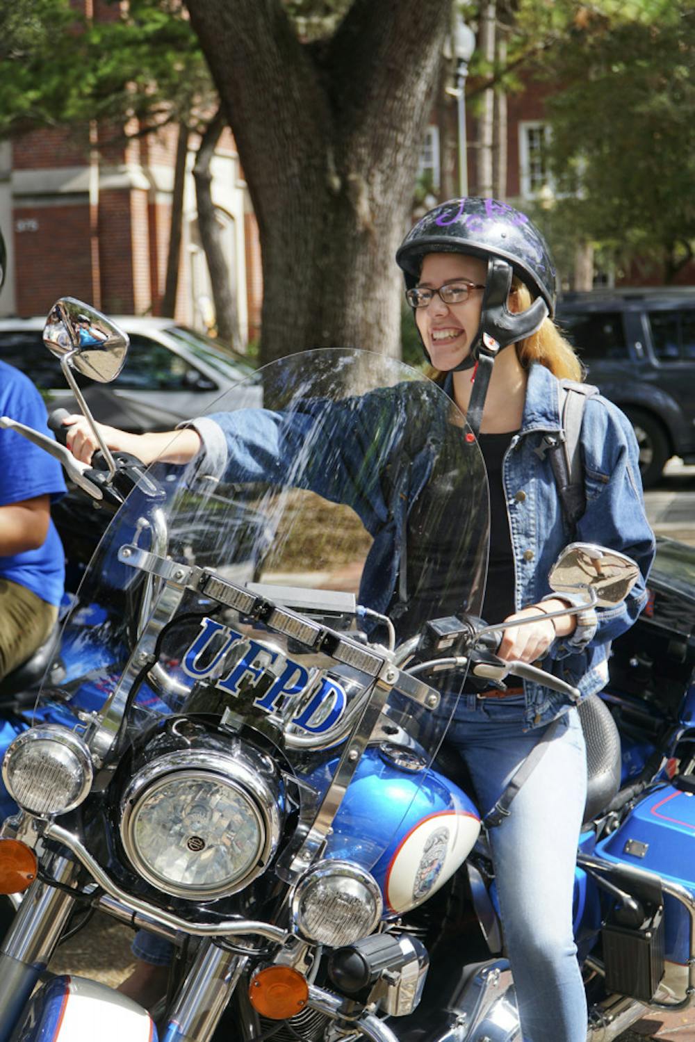 <p>Faith Percival, an 18-year-old UF nutritional sciences freshman, mounts a University Police motorcycle on Oct. 19, 2015, on Turlington Plaza. UPD helped raise awareness during scooter safety week by encouraging students to wear helmets.</p>