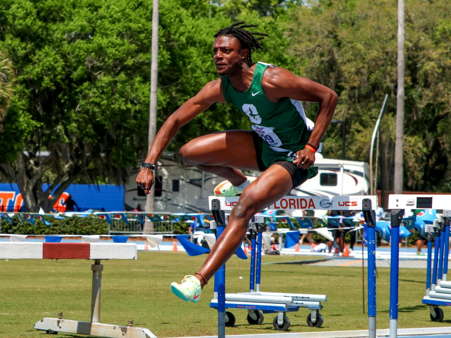 UNC Charlotte track and field athlete Sam Thompson clears a hurdle wearing a green uniform similar to his high school attire during the Pepsi Florida Relays Friday, March 31, 2023. Thompson was a student at UF before he transferred and joined UNC Charlotte&#x27;s team.