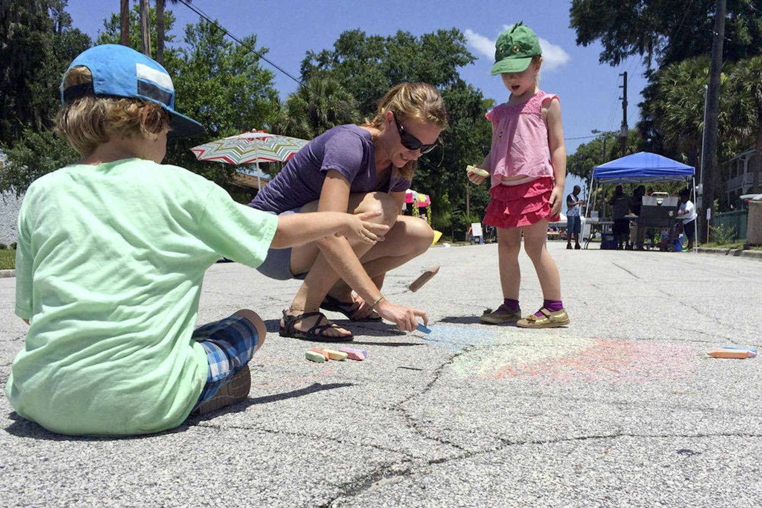 Vander Kubisek, 5, (left) Jill Kubisek, and Cece, 3, draw chalk pictures in the middle of Johnson Street at the Active Streets event in Hawthorne on Sunday morning. The Kubisek family attended past Active Streets events and decided to come out and support Hawthorne's businesses.