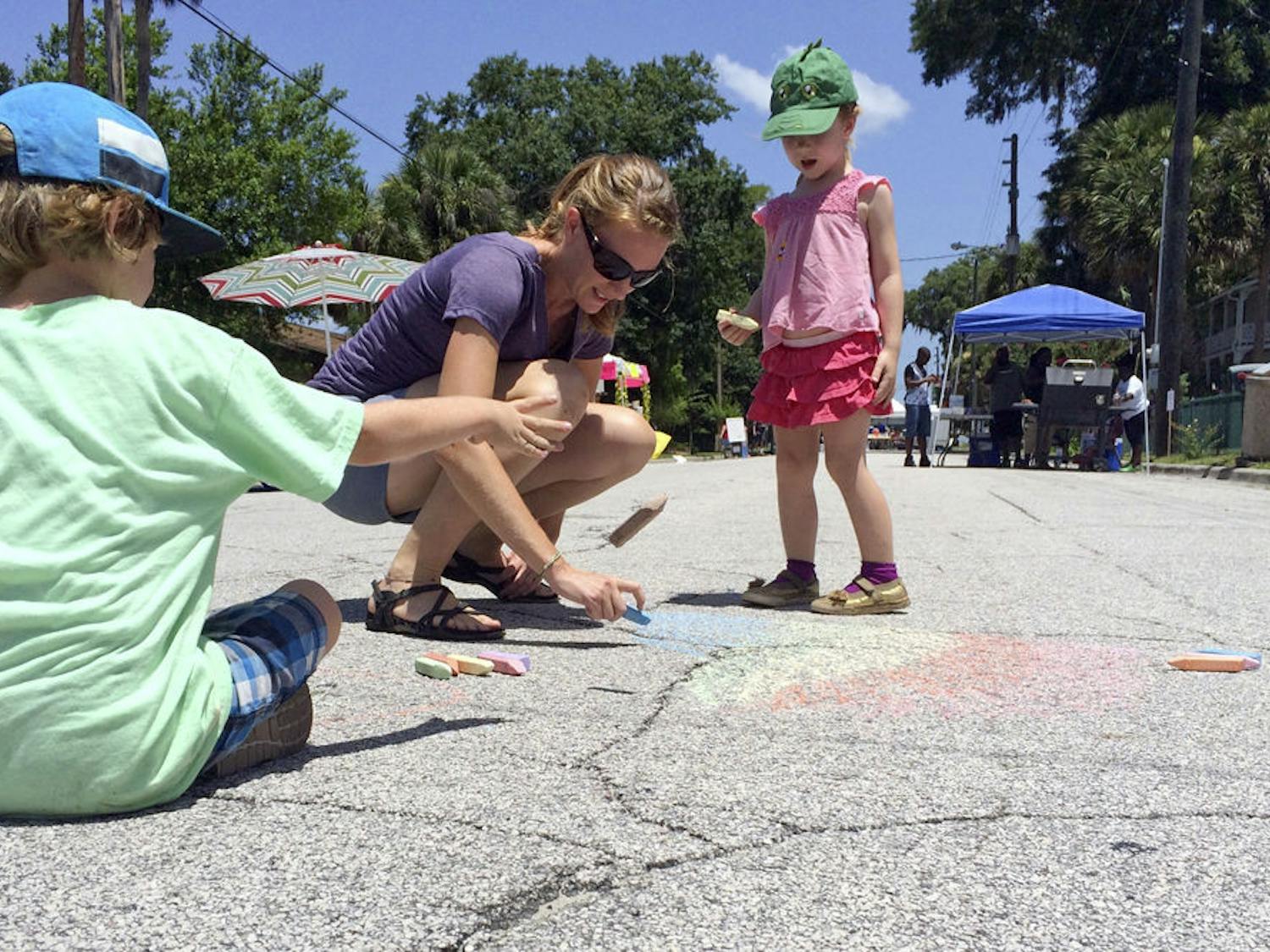 Vander Kubisek, 5, (left) Jill Kubisek, and Cece, 3, draw chalk pictures in the middle of Johnson Street at the Active Streets event in Hawthorne on Sunday morning. The Kubisek family attended past Active Streets events and decided to come out and support Hawthorne's businesses.