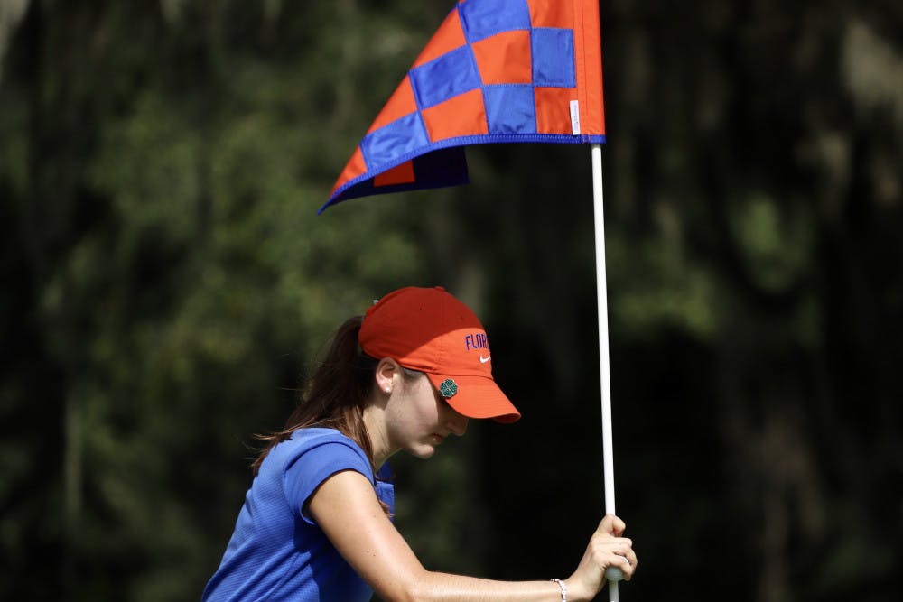 Freshman Maisie Filler adjusts a flag at Mark Bostick Golf Course. She won her final match of the fall season Wednesday.