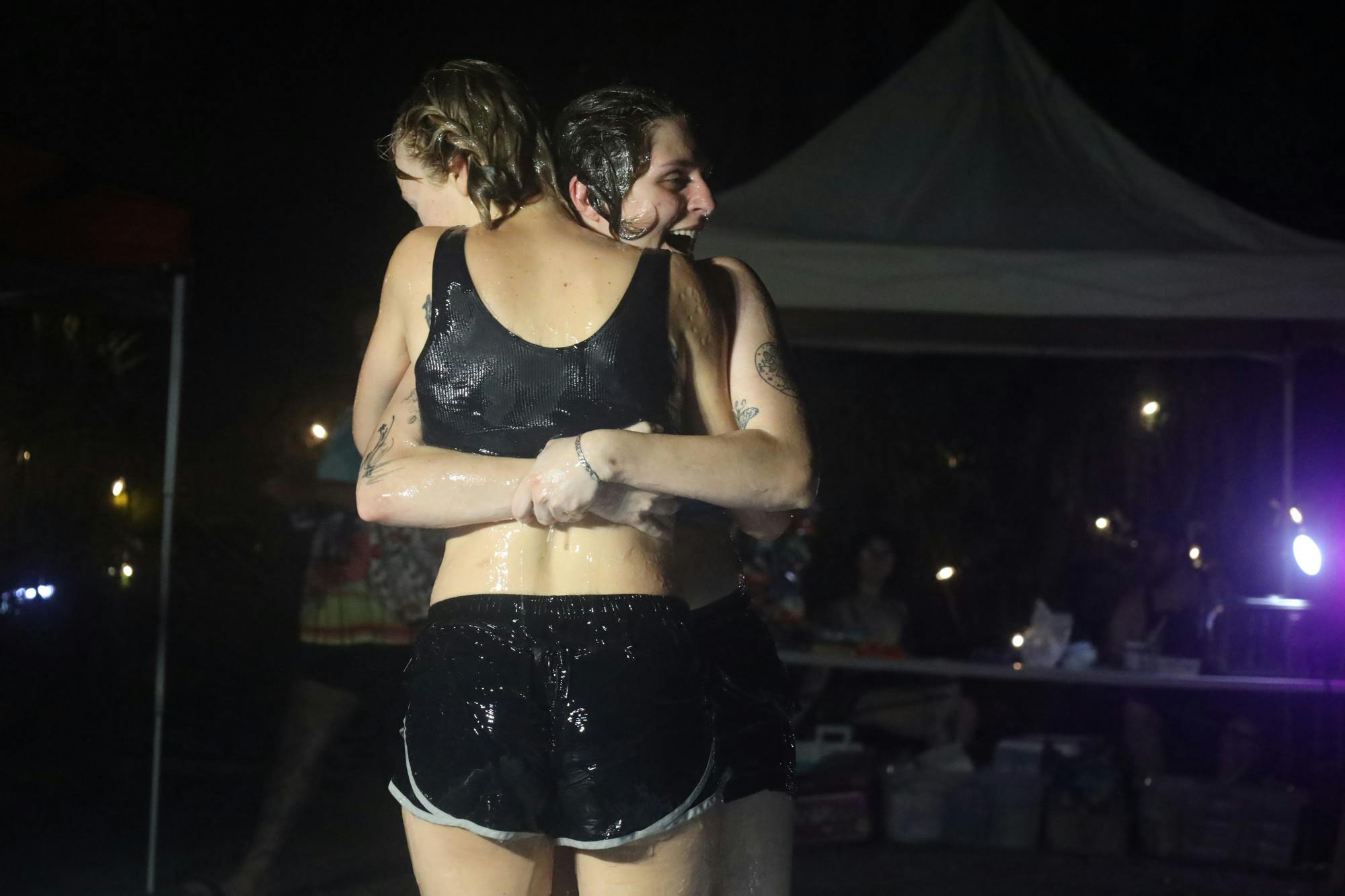 Two contestants embrace during lube wrestling fundraiser outside Serpentine Plants and Provisions, Saturday, April 4, in Gainesville, Fla.