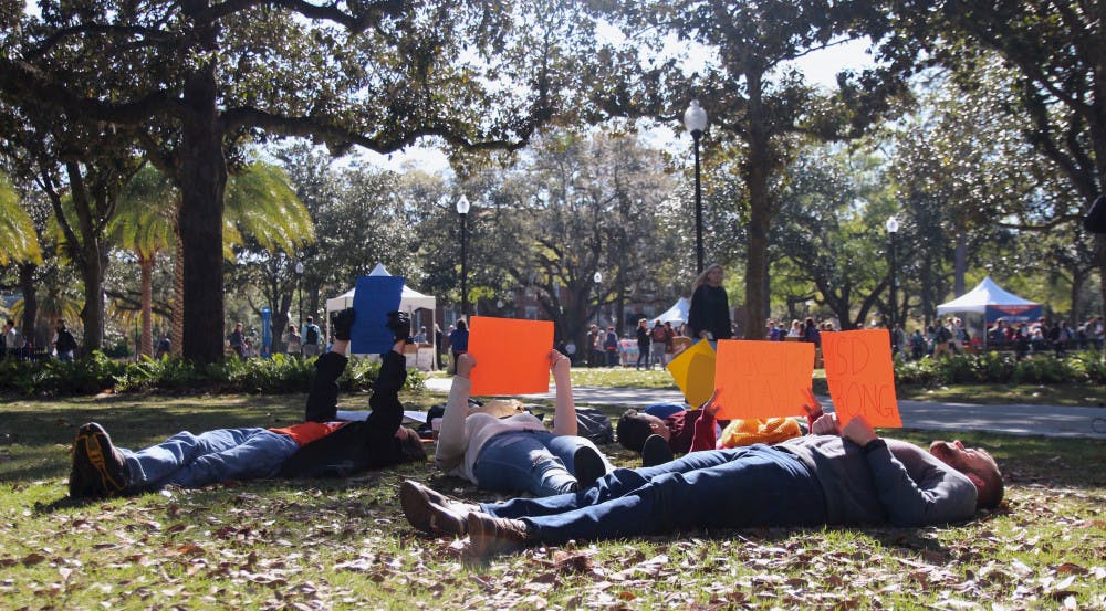 <p dir="ltr"><span>Students lie on the grass at Plaza of the Americas holding signs as a part of Indivisible UF's lie-down protest Wednesday morning. </span></p><p><span> </span></p>