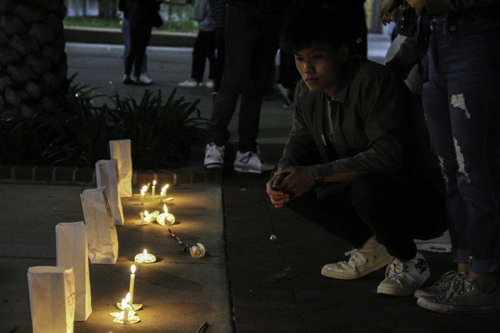 <p>Richard Doan, a 19-year-old business administration and telecommunication sophomore, solemnly pays respects during a vigil honoring the second anniversary of the Marjory Stoneman Douglas High School shooting that killed 17. The vigil was held on Plaza of the Americas Friday evening. </p>