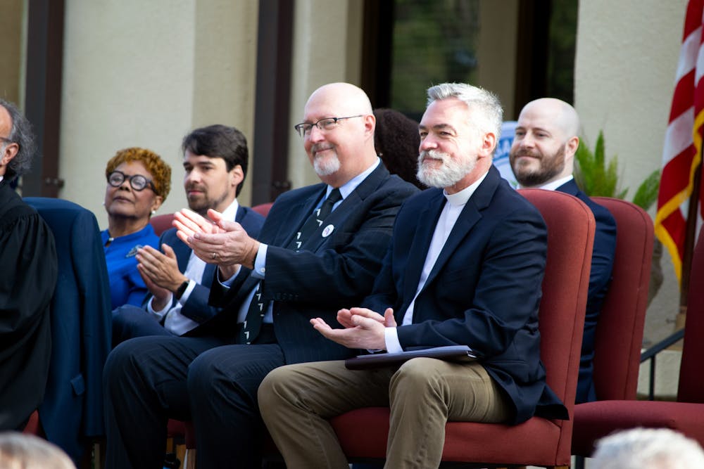 <p>Harvey Ward (left) and Rev. Fletcher of Holy Trinity Episcopal Church (right) clapping after a speech delivered at the swearing-in ceremony for Gainesville Mayor Thursday, Jan. 5, 2023. </p>