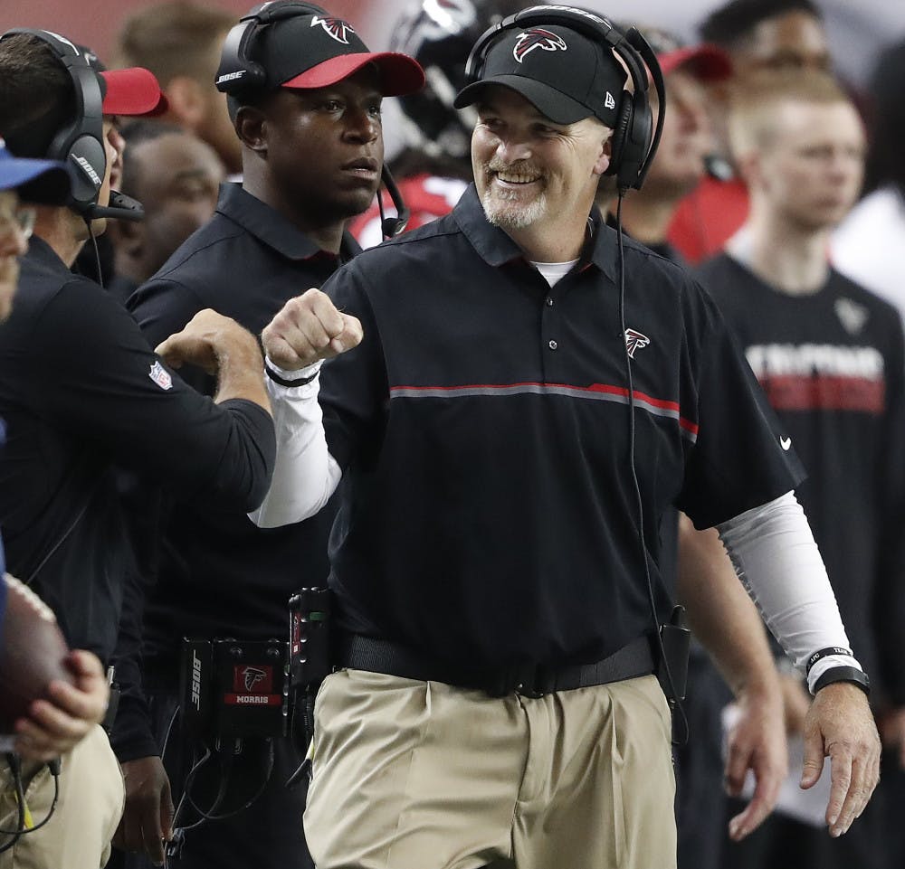 Atlanta Falcons head coach Dan Quinn fist bumps a coach after the Carolina Panthers were stopped during the first half of an NFL football game, Sunday, Oct. 2, 2016, in Atlanta. (AP Photo/John Bazemore)