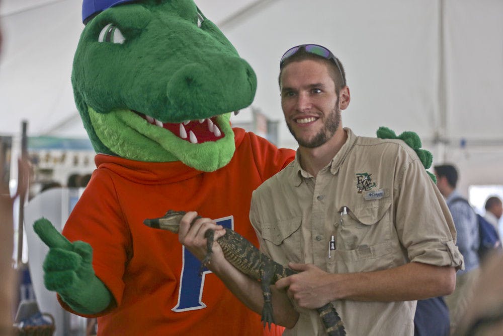 <p>Rob Cuskley, a 28-year-old biological scientist, introduces a baby american alligator to Albert during the campus showcase for Inauguration Week on Dec. 2, 2015. The Florida Museum of Natural History encouraged Cuskley to bring the alligator to educate students.</p>