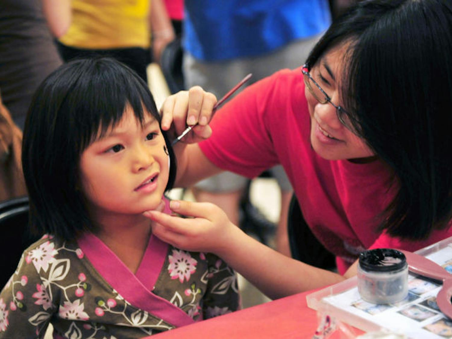 Elizabeth Wang, 19, a food science and human nutrition major at UF, paints 5-year-old Jenna Petty’s face Thursday night at the Museum Nights: Crouching Gator, Hidden Dragon! event hosted by the Samuel P. Harn Museum of Art.