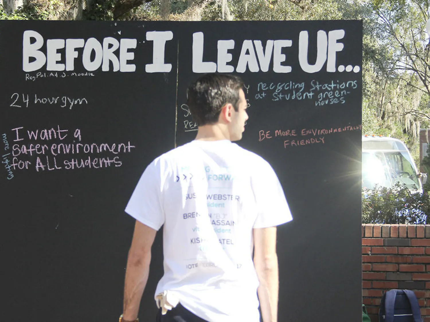 Blake Giragos, a UF graduate student in management and a member of Impact Party, encourages students to write changes they would like to see at UF before they graduate on a blackboard on Turlington Plaza on Tuesday.
