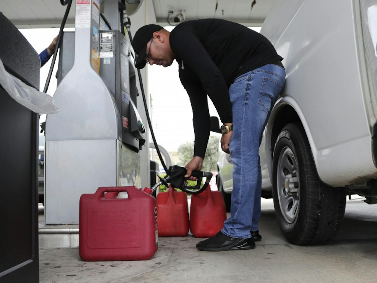 Arian Britto fills containers with gasoline at BJ's Wholesale Club in preparation for Hurricane Dorian, Thursday, Aug. 29, 2019, in Hialeah, Fla. Hurricane Dorian is heading towards Florida for a possible direct hit on the state over Labor Day. (AP Photo/Lynne Sladky)