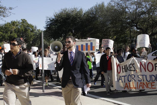 Jose Soto, a fourth-year Ph.D. candidate in food and resource economics, 31, left, and anthropology junior Robbey Hayes, 22, right, lead a group of about 60 protesters to Emerson Alumni Hall, where the UF Board of Trustees met Thursday. They rallied against tuition and fees increases.