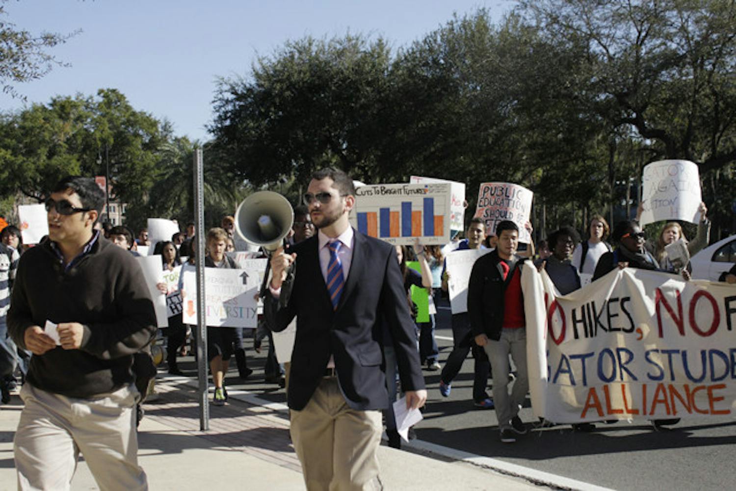 Jose Soto, a fourth-year Ph.D. candidate in food and resource economics, 31, left, and anthropology junior Robbey Hayes, 22, right, lead a group of about 60 protesters to Emerson Alumni Hall, where the UF Board of Trustees met Thursday. They rallied against tuition and fees increases.